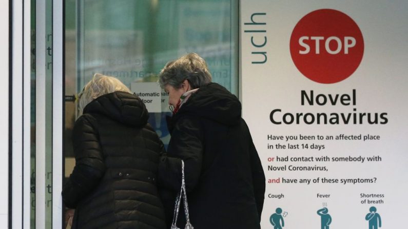 Dos mujeres pasan por delante de un cartel que proporciona información orientativa sobre el nuevo coronavirus COVID-19 en una de las entradas del Hospital Universitario de Londres, Reino Unido, el 5 de marzo de 2020. (ISABEL INFANTES/AFP vía Getty Images)