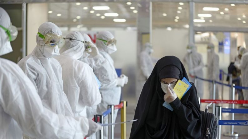 Personal médico con equipo de protección distribuye hojas informativas a los pasajeros iraquíes que regresan del Irán en el Aeropuerto Internacional de Najaf (Irak) el 5 de marzo de 2020. (HAIDAR HAMDANI/AFP vía Getty Images)