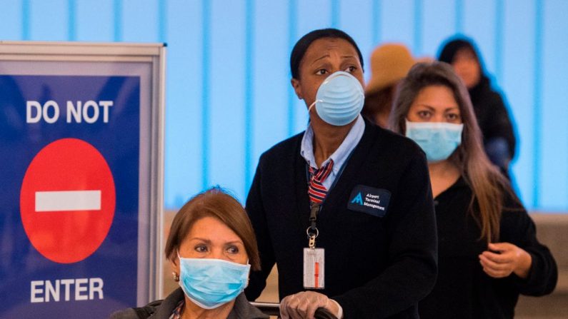 Los pasajeros llevan máscaras para protegerse del virus del PCCh después de llegar al aeropuerto de Los Ángeles, California, el 5 de marzo de 2020.  (Foto de MARK RALSTON/AFP vía Getty Images)
