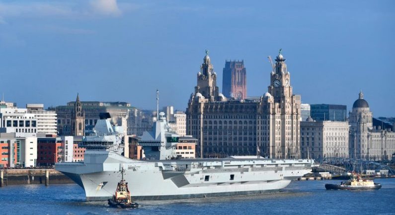 Remolcadores maniobran el HMS Príncipe de Gales de la Marina Real Británica, mientras se prepara para abandonar los muelles de Liverpool, al noroeste de Inglaterra, el 6 de marzo de 2020. (PAUL ELLIS/AFP vía Getty Images)