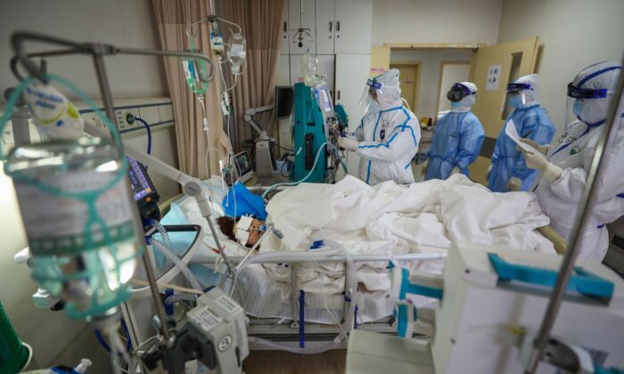 Foto tomada el 6 de marzo de 2020 muestra a personal médico revisando a un paciente con coronavirus COVID-19 en el hospital de la Cruz Roja en Wuhan en la provincia central de Hubei en China. (STR/AFP vía Getty Images)