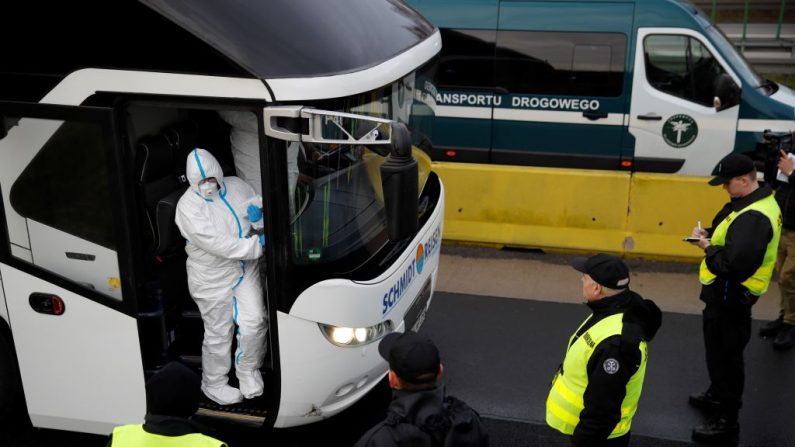 Una fotografía tomada el 9 de marzo de 2020 en el lado polaco muestra a la policía y al personal médico polacos, con ropa de protección, procediendo a los controles sanitarios de los conductores en el cruce fronterizo de Jedrzychowice, entre Polonia y Alemania, en una medida de protección contra la propagación del nuevo coronavirus. (ODD ANDERSEN/AFP vía Getty Images)