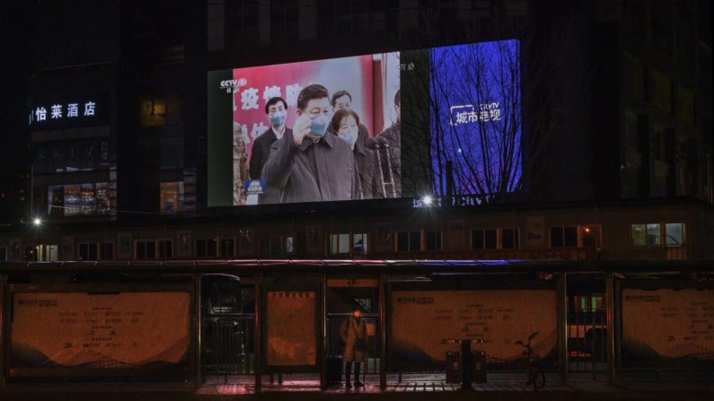 Una gran pantalla en la calle muestra al líder chino Xi Jinping usando una máscara protectora durante su visita a Wuhan, el epicentro del coronavirus, en el noticiero vespertino de CCTV en Beijing el 10 de marzo de 2020. (Kevin Frayer/Getty Images)