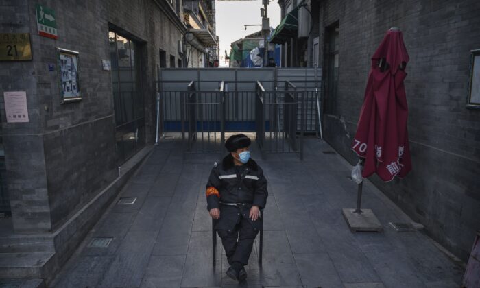 Un guardia chino con máscara facial mientras vigila una zona cerca de una barricada que bloquea una comunidad residencial de una zona comercial en Beijing el 11 de marzo de 2020. (Kevin Frayer/Getty Images)