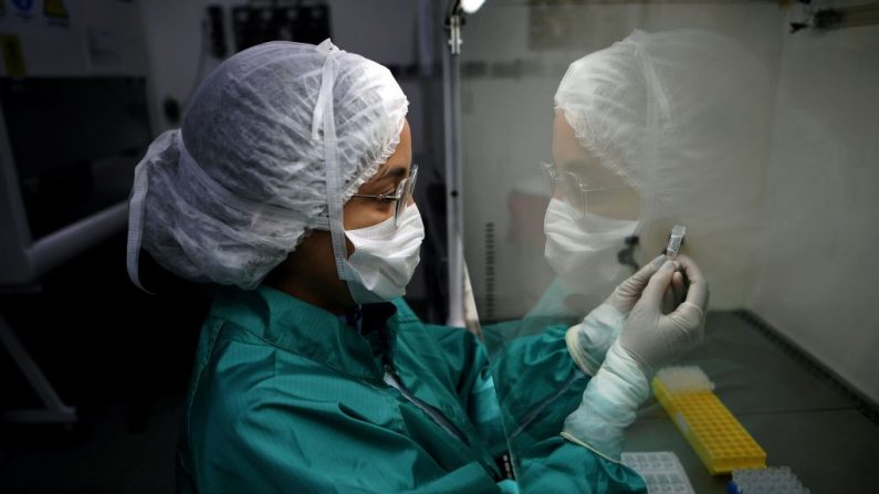 Un analista del laboratorio Fiocruz, un instituto de investigación de salud pública, en Río de Janeiro, tiene una muestra de moco para ser analizada para COVID-19, el 11 de marzo de 2020. (Foto de CARL DE SOUZA/AFP vía Getty Images)
