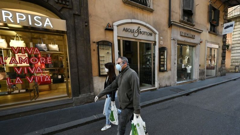 Los residentes llevan sus compras a través de Via del Corso en el centro de Roma el 12 de marzo de 2020. Italia cerró todas las tiendas, excepto las farmacias y las tiendas de alimentos, en un intento desesperado por detener la propagación de coronavirus. (VINCENZO PINTO/AFP a través de Getty Images)