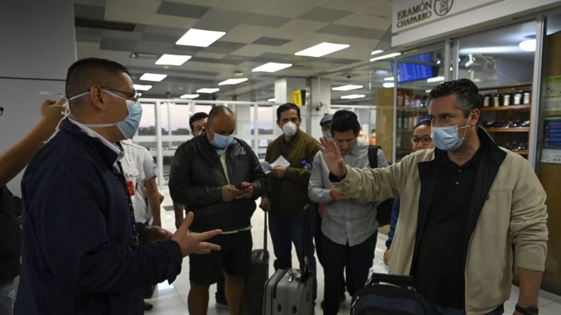 Los pasajeros a los que se les negó la entrada a El Salvador antes de que completen la cuarentena, hablan con un funcionario (L) que lleva una máscara facial como precaución contra la propagación del nuevo coronavirus, COVID-19, en el Aeropuerto Internacional San Oscar Romero de San Luis Talpa, El Salvador, el 12 de marzo de 2020. (Foto de MARVIN RECINOS/AFP vía Getty Images)
