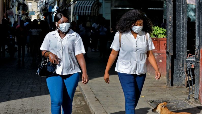 Las mujeres llevan máscaras protectoras para prevenir la propagación del virus del PCCh mientras caminan por las calles de La Habana, Cuba, el 12 de marzo de 2020. (YAMIL LAGE/AFP vía Getty Images)
