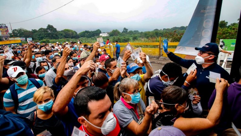 Personas provenientes de Venezuela con máscaras faciales de protección como medida de precaución para evitar contraer el nuevo coronavirus, COVID-19, muestran sus documentos en la frontera en el Puente Internacional Simón Bolívar, en Cúcuta, Colombia, el 12 de marzo de 2020. (Foto de SCHNEYDER MENDOZA/AFP vía Getty Images)
