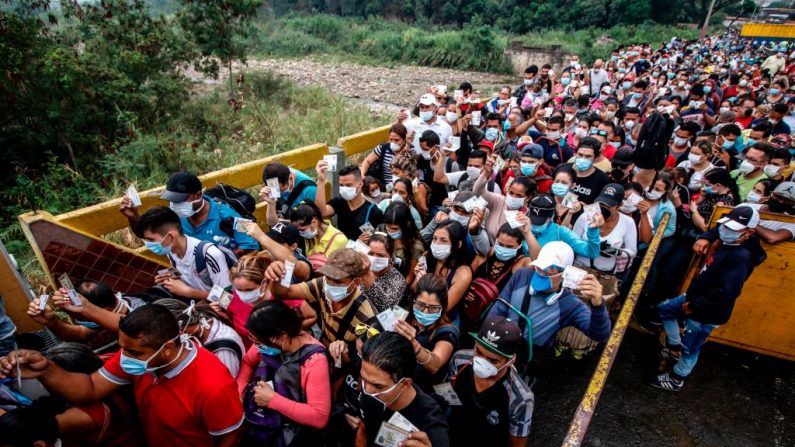 Personas provenientes de Venezuela con máscaras faciales de protección como medida de precaución para evitar contraer el nuevo coronavirus, COVID-19, muestran sus documentos en la frontera en el Puente Internacional Simón Bolívar, en Cúcuta, Colombia, el 12 de marzo de 2020. (Foto de SCHNEYDER MENDOZA/AFP vía Getty Images)
