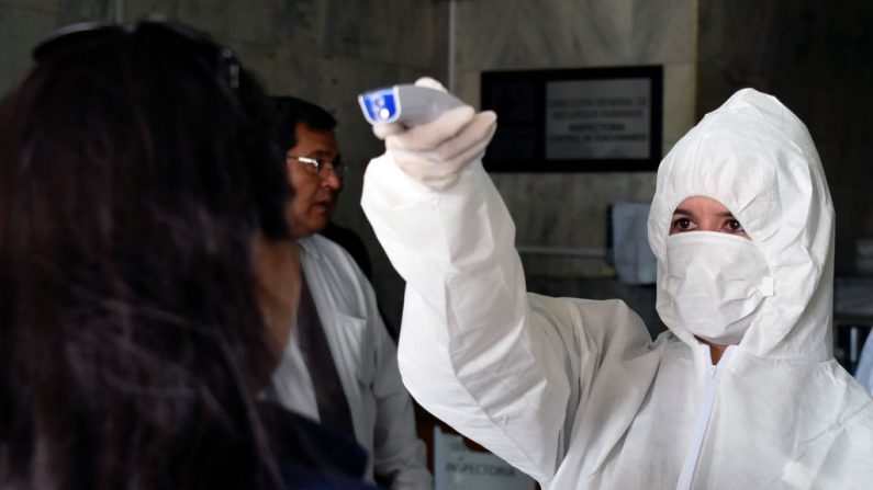 Un trabajador de la salud revisa la temperatura a los que entran al Palacio de Justicia, como parte de las medidas preventivas del gobierno para mitigar la propagación del virus del PCCh, en Asunción, el 13 de marzo de 2020. (Foto de NORBERTO DUARTE/AFP vía Getty Images)
