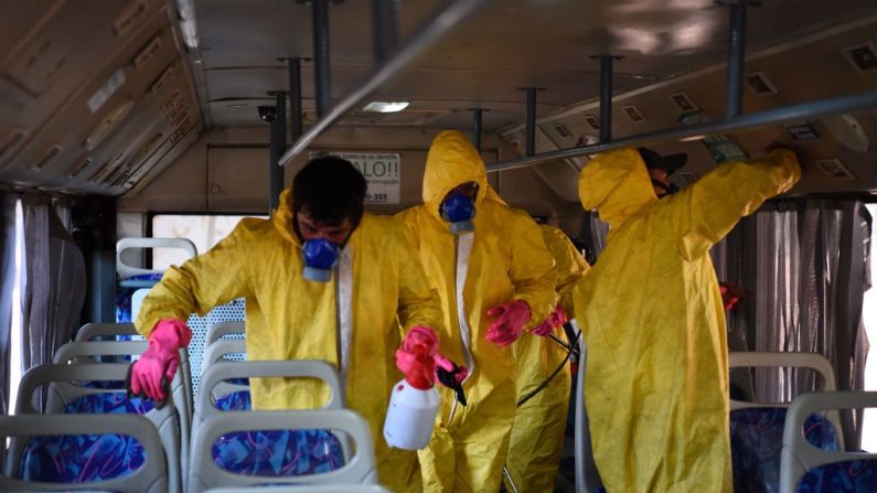 Empleados de una empresa de autobuses fumigan un autobús, como parte de las medidas preventivas del gobierno para mitigar la propagación del Coronavirus COVID-19, en Asunción, el 13 de marzo de 2020. (Foto de NORBERTO DUARTE/AFP vía Getty Images)
