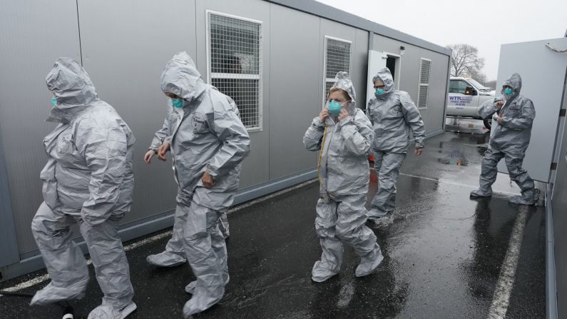 Trabajadores en trajes protectores se preparan mientras esperan a que las personas se sometan a pruebas de detección del Coronavirus (COVID-19) al llegar en coche al laboratorio móvil de pruebas para coronavirus del Estado en Glen Island Park en Nueva Rochelle, Nueva York, el 13 de marzo de 2020. (Foto de TIMOTHY A. CLARY/AFP vía Getty Images)