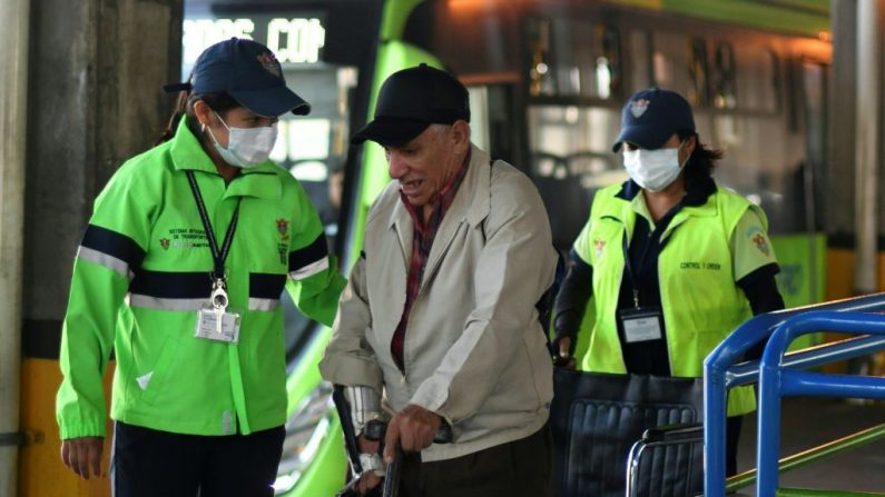 Funcionarios municipales con máscaras de protección, como medida preventiva contra la propagación del Coronavirus COVID-19, ayudan a un pasajero de edad avanzada en la terminal de autobuses de la Ciudad de Guatemala (Guatemala) el 13 de marzo de 2020. (JOHAN ORDONEZ/AFP vía Getty Images)