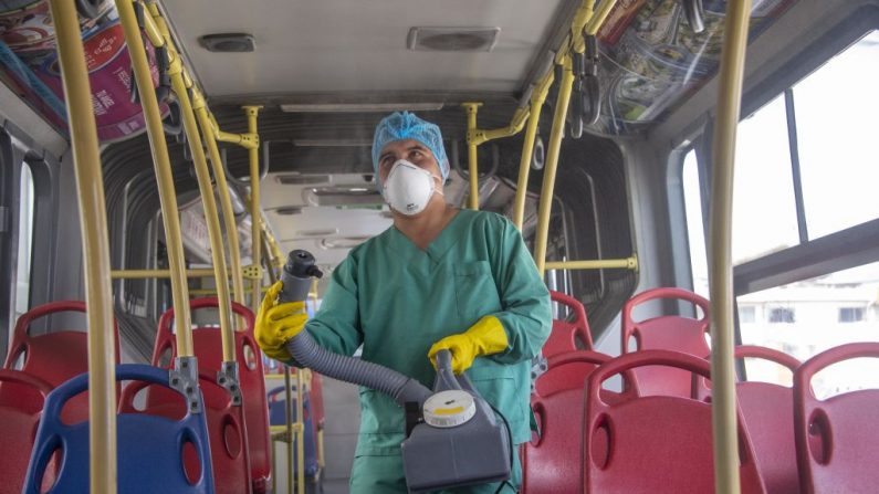 Un trabajador desinfecta un autobús como medida preventiva contra la propagación del Coronavirus COVID-19, en una estación de transferencia en Quito, Ecuador, el 13 de marzo de 2020. (RODRIGO BUENDIA/AFP vía Getty Images)