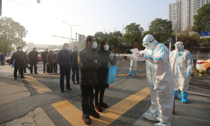 Trabajadores médicos (vestidos con trajes protectores) revisan a los pacientes que se han recuperado del coronavirus, COVID-19, cuando llegan para ser examinados de nuevo en un hospital de Wuhan, China, el 14 de marzo de 2020. (STR/AFP a través de Getty Images)