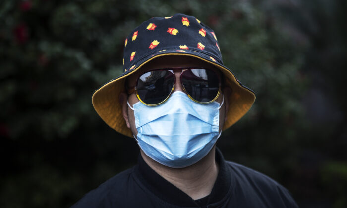 Un hombre lleva una máscara facial en un muro de barricada improvisado que tiene por objeto controlar la entrada y salida de visitantes a un complejo residencial en Wuhan, China, el 14 de marzo de 2020. (Stringer/Getty Images)