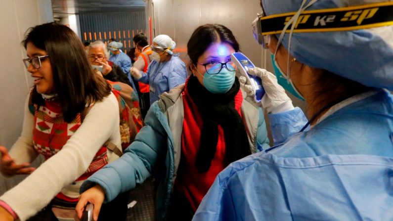El personal médico comprueba la temperatura del viajero al desembarcar a su llegada al aeropuerto internacional Jorge Chávez en Callao, Lima, Perú, el 16 de marzo de 2020, en el último vuelo desde EE.UU. antes de que se cierren las fronteras. (LUKA GONZALES/AFP vía Getty Images)