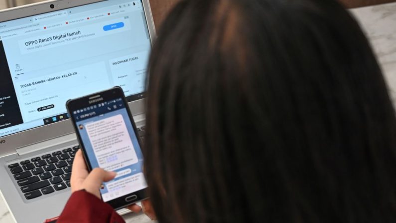 Una estudiante participa en una clase en línea desde su casa usando su computadora portátil y su teléfono inteligente para charlar con los maestros durante las próximas dos semanas en Yakarta el 17 de marzo de 2020, en medio de las preocupaciones por el brote del coronavirus COVID-19. (Bay Ismoyo/AFP vía Getty Images)