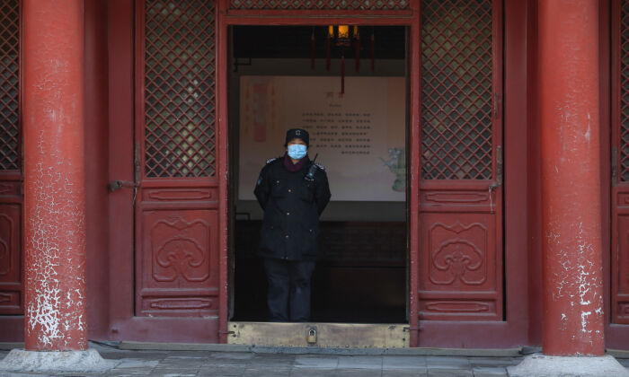 Un guardia de seguridad con una máscara facial mira el Palacio Imperial cuando se reabre al público en Shenyang, China, el 17 de marzo de 2020. (STR/AFP vía Getty Images)