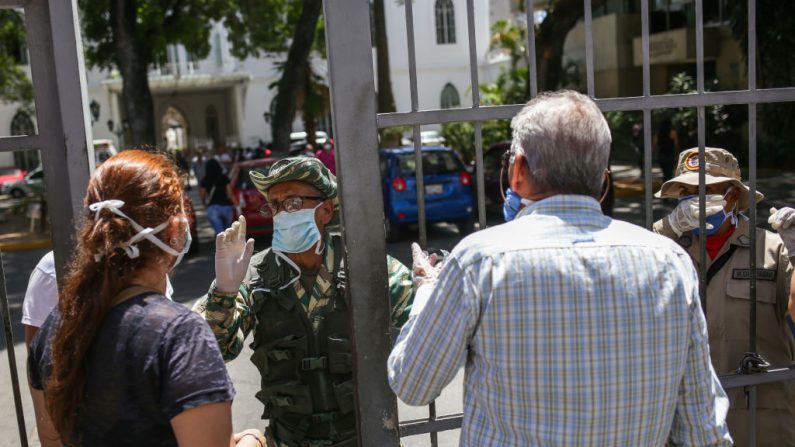 Los miembros de la milicia bolivariana llevan máscaras faciales como medida preventiva contra la propagación del virus del PCCh, mientras hacen guardia en la puerta del Hospital Vargas de Caracas, Venezuela, el 17 de marzo de 2020. (CRISTIAN HERNANDEZ/AFP vía Getty Images)