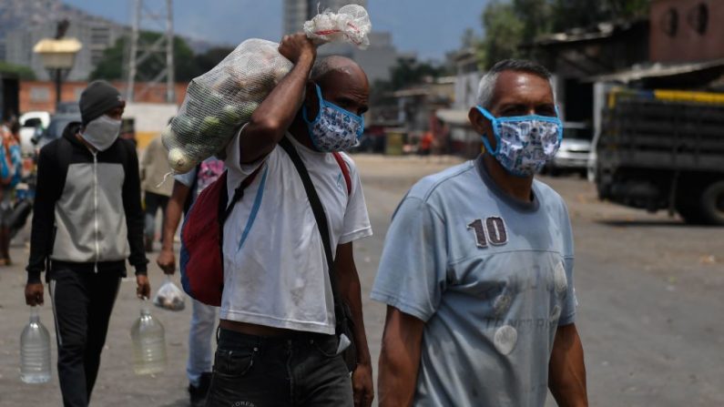 La gente usa máscaras faciales cuando compra en un mercado municipal como medida preventiva contra el virus del PCCh, en Caracas, Venezuela, el 18 de marzo de 2020. (FEDERICO PARRA/AFP vía Getty Images)