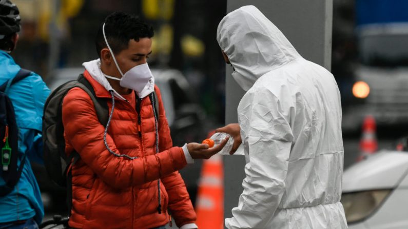 Un joven que lleva una suite protectora aplica desinfectante de manos a un hombre como parte de una campaña de concienciación contra la propagación del virus del PCCh. (JUAN BARRETO/AFP vía Getty Images)