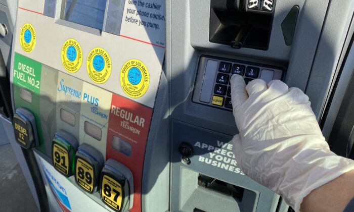 Una mujer usa un guante como medida preventiva contra el virus del PCCh en una gasolinera de Los Ángeles el 18 de marzo de 2020. (Chris Delmas/AFP a través de Getty Images)