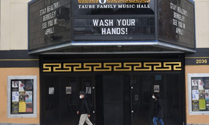 Personas con mascarillas faciales caminan por un teatro cerrado con un mensaje sobre lavar sus manos en Berkeley, California, el 18 de marzo de 2020. (Josh Edelson / AFP a través de Getty Images)