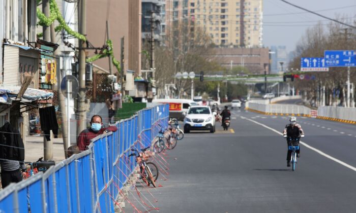 Un hombre mira encima de una barrera establecida para evitar que las personas entren o salgan de un complejo residencial en Wuhan, China, el 17 de marzo de 2020. (STR / AFP a través de Getty Images)