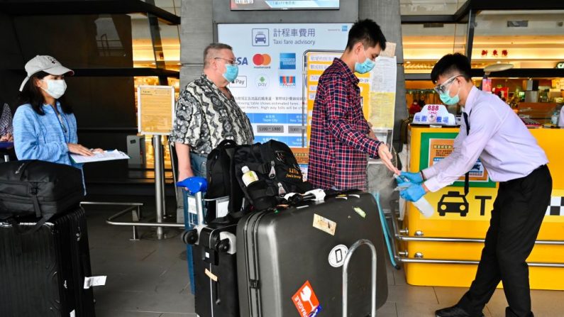 Un trabajador rocía desinfectante de manos sobre pasajeros luego de que llegan al aeropuerto internacional de Taoyuan en Taiwán el 19 de marzo de 2020. (Sam Yeh/AFP a través de Getty Images)
