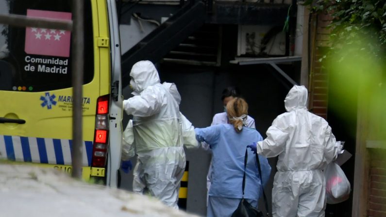 Trabajadores sanitarios con trajes protectores acompañan a un paciente a su llegada al Gran Hotel Colón de Madrid, España, un primer hotel que se transformó en una estructura médica para tratar los casos menos graves en medio del brote causado por el virus del PCCh, el 19 de marzo de 2020. (GABRIEL BOUYS/AFP vía Getty Images)