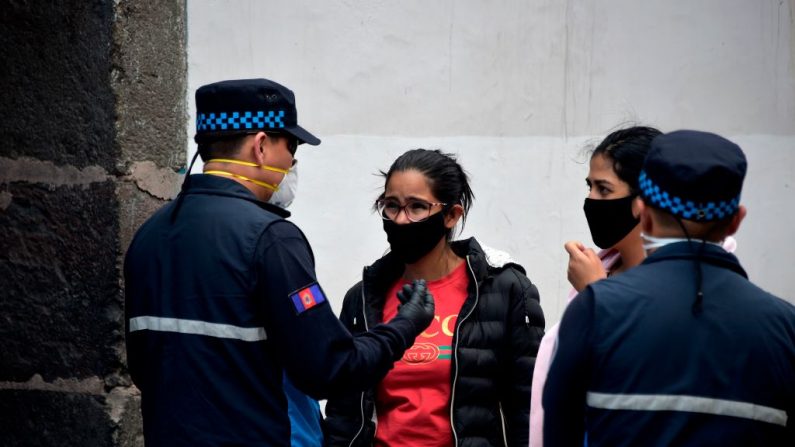 Un policía habla a las peatones durante el estado de emergencia en la Plaza Grande de Quito, Ecuador, el 19 de marzo de 2020. (RODRIGO BUENDIA/AFP vía Getty Images)