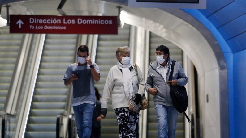 Los viajeros caminan con máscaras faciales en una estación mientras el tren subterráneo sigue funcionando pero con un bajo flujo de pasajeros debido a la pandemia del virus del PCCh del 20 de marzo de 2020 en Santiago de Chile. (Marcelo Hernandez/Getty Images)