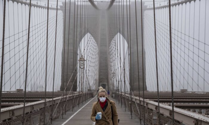 Una mujer con mascarilla camina por el Puente de Brooklyn en la niebla durante el brote del coronavirus (COVID-19) en la ciudad de Nueva York el 20 de marzo de 2020. (Victor J. Blue/Getty Images)