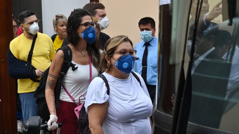 Ciudadanos brasileños suben a un autobús que los lleva al aeropuerto internacional Jorge Chávez en el Callao, frente al consulado brasileño en Lima, Perú, el 20 de marzo de 2020, debido al bloqueo por el virus del PCCh. (CRIS BOURONCLE/AFP vía Getty Images)