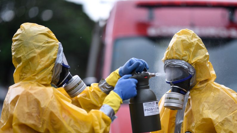 Los bomberos que llevan trajes de protección participan en una instrucción como forma de contingencia y seguridad contra la propagación del virus del PCCh, en Belo Horizonte, estado de Minas Gerais, Brasil, el 20 de marzo de 2020. (DOUGLAS MAGNO/AFP vía Getty Images)