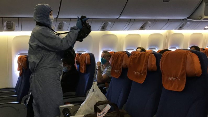 Un funcionario ruso comprueba las temperaturas de los pasajeros dentro de un avión momentos después de que aterrizara desde Beijing en el aeropuerto Sheremetyevo de Moscú el 21 de marzo de 2020 en medio de los temores de la propagación del COVID-19. (Foto de LAURENT THOMET/AFP vía Getty Images)