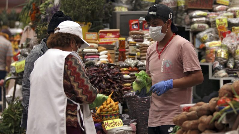 La gente usa máscaras y guantes para prevenir la propagación del virus del PCCh en el mercado de Santa Clara en Quito, el 21 de marzo de 2020. (CRISTINA VEGA RHOR / AFP vía Getty Images)