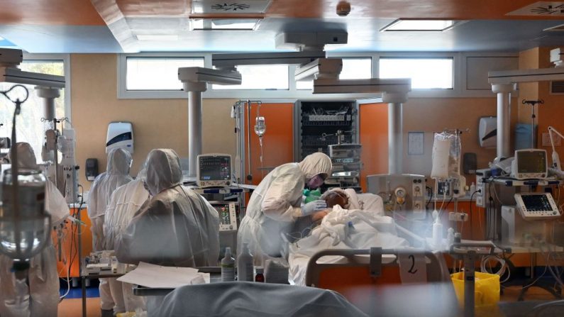 Un trabajador médico con equipo de protección (c) atiende a un paciente el 24 de marzo de 2020 en la nueva unidad de cuidados intensivos de nivel 3 para casos del virus del PCCh en el hospital Casal Palocco cerca de Roma, Italia, durante el cierre del país con el fin de detener la propagación de la pandemia del virus. (ALBERTO PIZZOLI/AFP vía Getty Images)