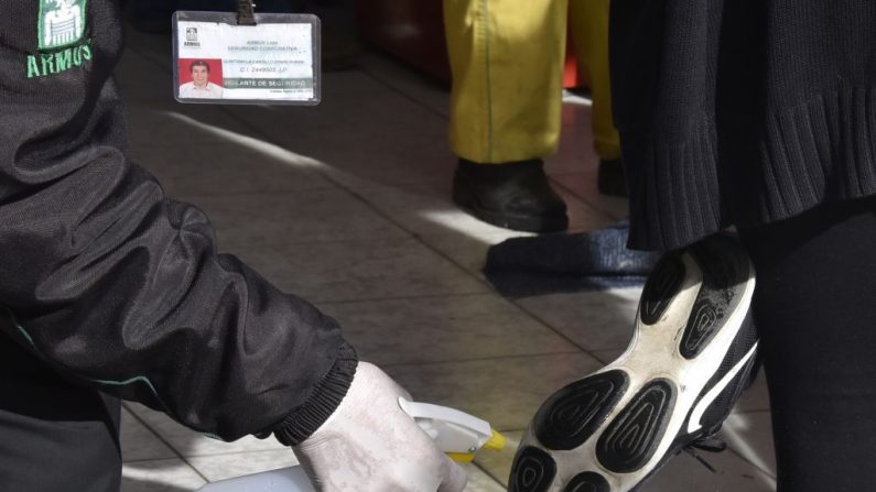 Un trabajador desinfecta los zapatos de un cliente a la entrada de un mercado como medida preventiva contra la propagación del nuevo coronavirus, COVID-19, en un mercado de La Paz, Bolivia el 26 de marzo de 2020. (AIZAR RALDES/AFP vía Getty Images)