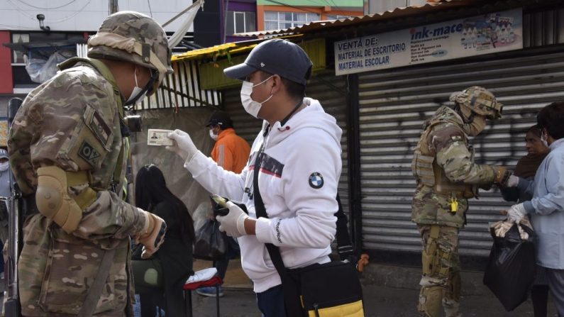 Miembros de la policía militar revisan los documentos de identificación de las personas que pasan por las calles después de que la presidente interina de Bolivia, Jeanine Añez, anunciara el cierre de las fronteras y la prohibición de cualquier movimiento dentro del país hasta el 15 de abril, como medida preventiva contra la propagación del virus del PCCh, en La Paz, Bolivia, el 26 de marzo de 2020. (AIZAR RALDES/AFP vía Getty Images)