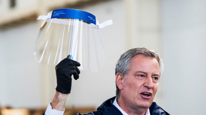 El alcalde de Nueva York, Bill de Blasio, sostiene un protector facial mientras habla con los medios de comunicación durante una visita al Astillero Naval de Brooklyn, donde las empresas industriales locales han comenzado a fabricar Equipo de Protección Personal (PPE) el 26 de marzo de 2020 en la ciudad de Nueva York. En todo el país, escuelas, empresas y lugares de trabajo han sido cerrados o están restringiendo las horas de operación mientras los funcionarios de salud tratan de frenar la propagación de COVID-19. (Eduardo Muñoz Álvarez/Getty Images)