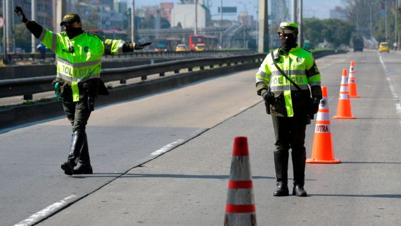 Agentes de policía con máscaras faciales como medida preventiva contra la propagación del virus del PCCh, paran los vehículos que circulan por las calles de Bogotá, Colombia, el 27 de marzo de 2020. (Raúl ARBOLEDA/AFP vía Getty Images)