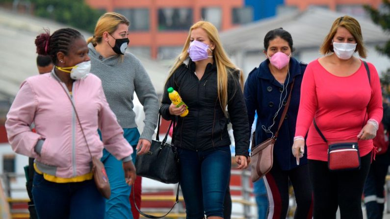Las personas que usan máscaras faciales, como medida preventiva contra la propagación del virus del PCCh, caminan en la calle, en Soacha, cerca de Bogotá, Colombia, el 31 de marzo de 2020. (Raúl ARBOLEDA/AFP vía Getty Images)