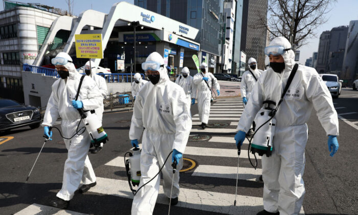 Soldados surcoreanos con equipo de protección rocían solución antiséptica para combatir el nuevo coronavirus en el distrito de Gangnam en Seúl, Corea del Sur, el 6 de marzo de 2020. (Chung Sung-Jun/Getty Images)