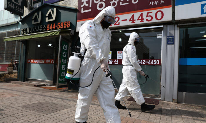 Soldados surcoreanos, con equipo de protección, rocían solución antiséptica para protegerse del coronavirus a lo largo de una calle del distrito de Gangnam en Seúl, Corea del Sur, el 9 de marzo de 2020. (Chung Sung-Jun/Getty Images)