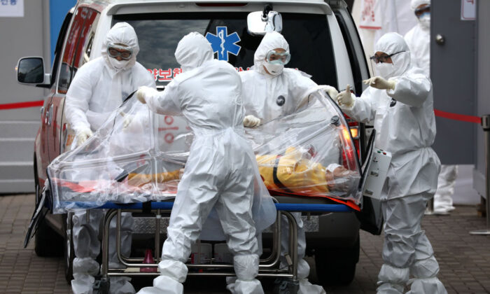 El personal médico que lleva equipo de protección traslada a un paciente infectado con el nuevo coronavirus de una ambulancia a un hospital en Seúl el 9 de marzo de 2020. (Chung Sung-Jun/Getty Images)