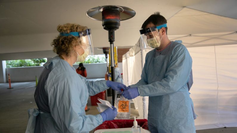 Enfermeros con ropa de protección manipulan una bolsa con un hisopo potencielmente infectado con coronavirus en un centro de pruebas de la Universidad de Washington Medical el 13 de marzo de 2020 en Seattle, Washington.  (John Moore/Getty Images)