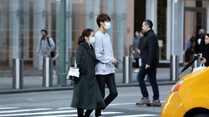 Una pareja con máscaras protectoras es vista cruzando la calle el 13 de marzo de 2020 en la ciudad de Nueva York, EE.UU. (Cindy Ord/Getty Images)